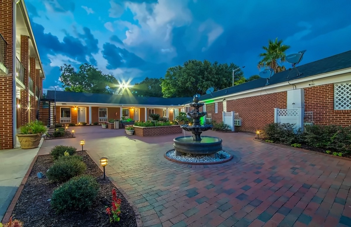 The brick courtyard at Winton Inn & Suites at dusk, with a fountain and softly lit walkways