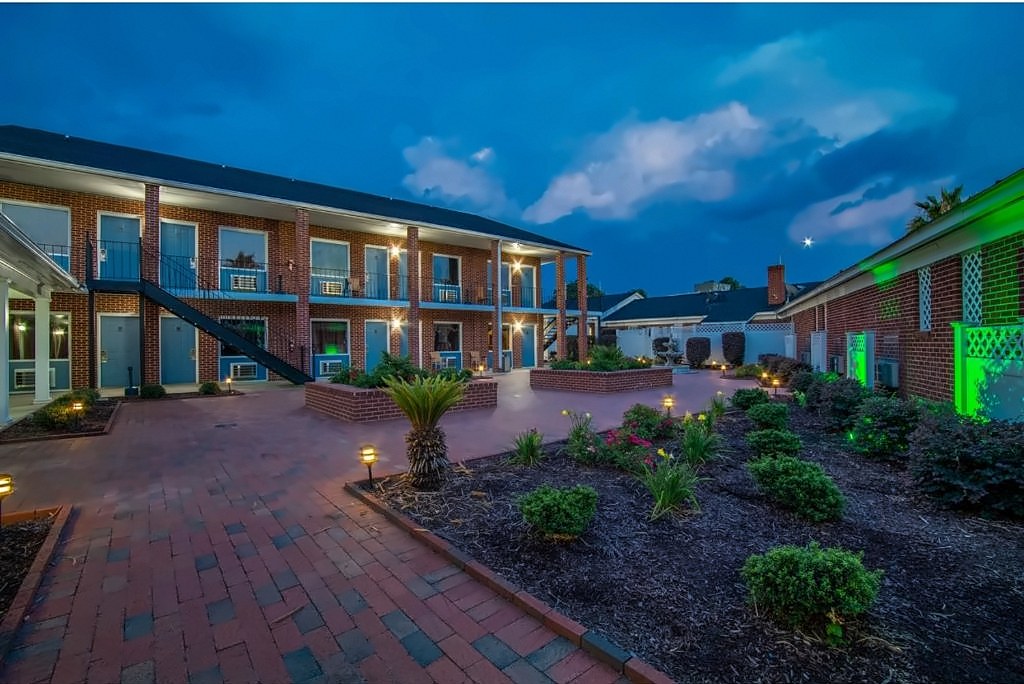 The two-story guest building around the courtyard at Winton Inn & Suites at dusk, with warm lights on