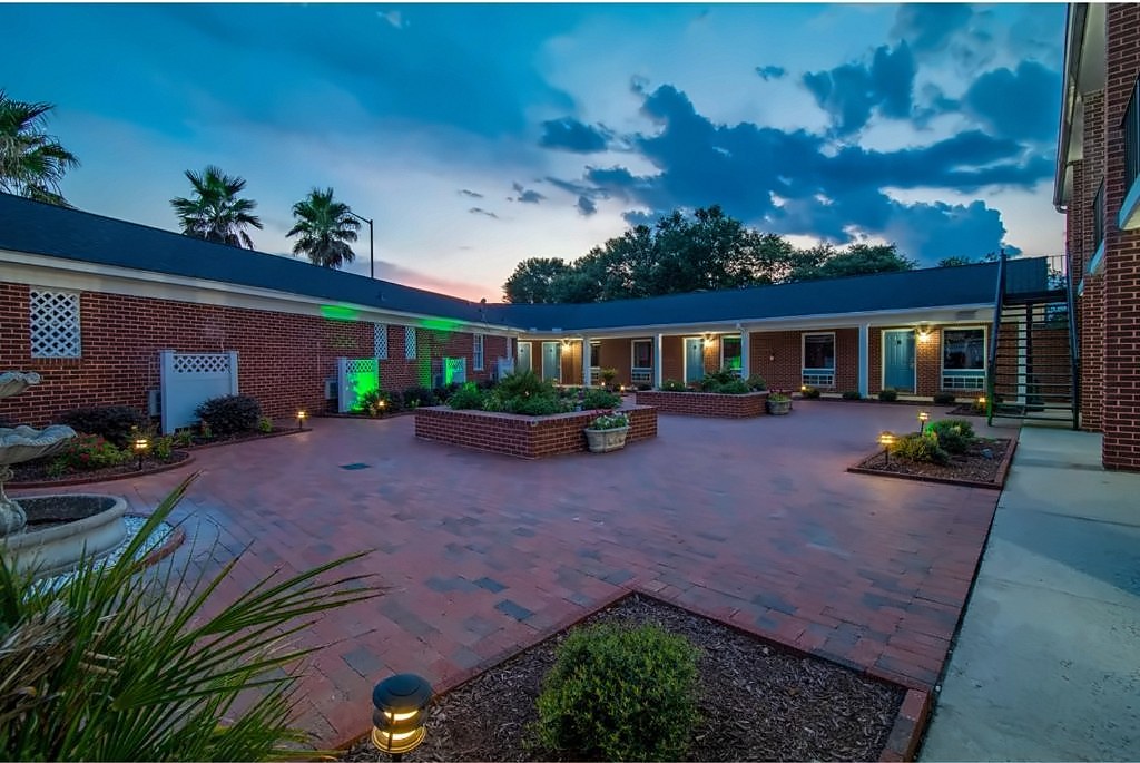 The courtyard at Winton Inn & Suites after dark, with garden beds and soft landscape lighting