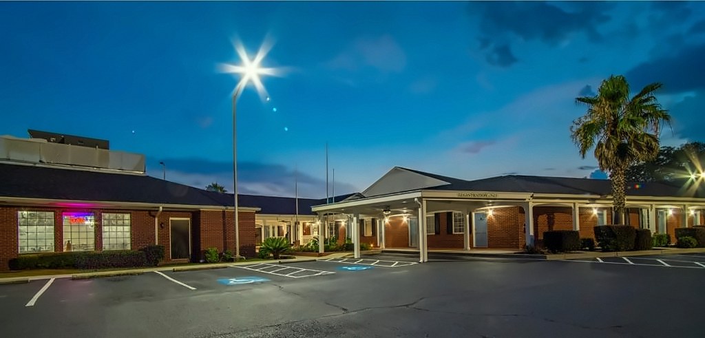 The front of Winton Inn & Suites at dusk, with the covered entrance and a large parking area