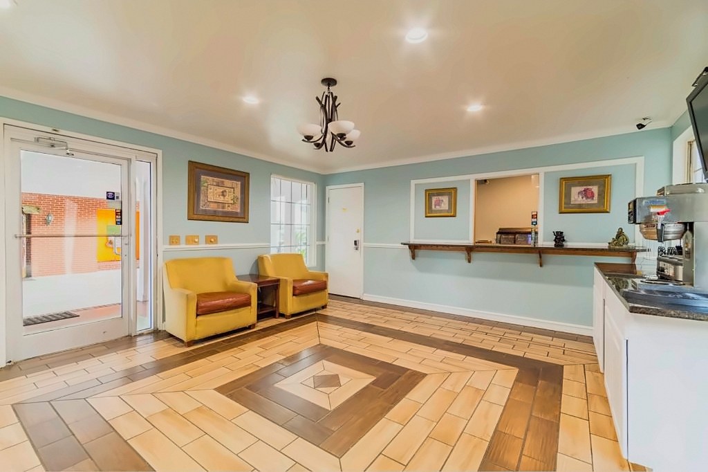 The lobby at Winton Inn & Suites with two armchairs, a patterned tile floor and the front desk window